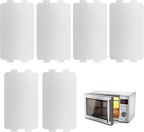Six plaques de mica rectangulaires, une à plat et cinq empilées sur un plan de travail clair.