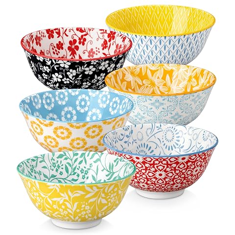 Six bols en porcelaine aux motifs floraux pastel, un devant et cinq empilés sur un plan de travail.